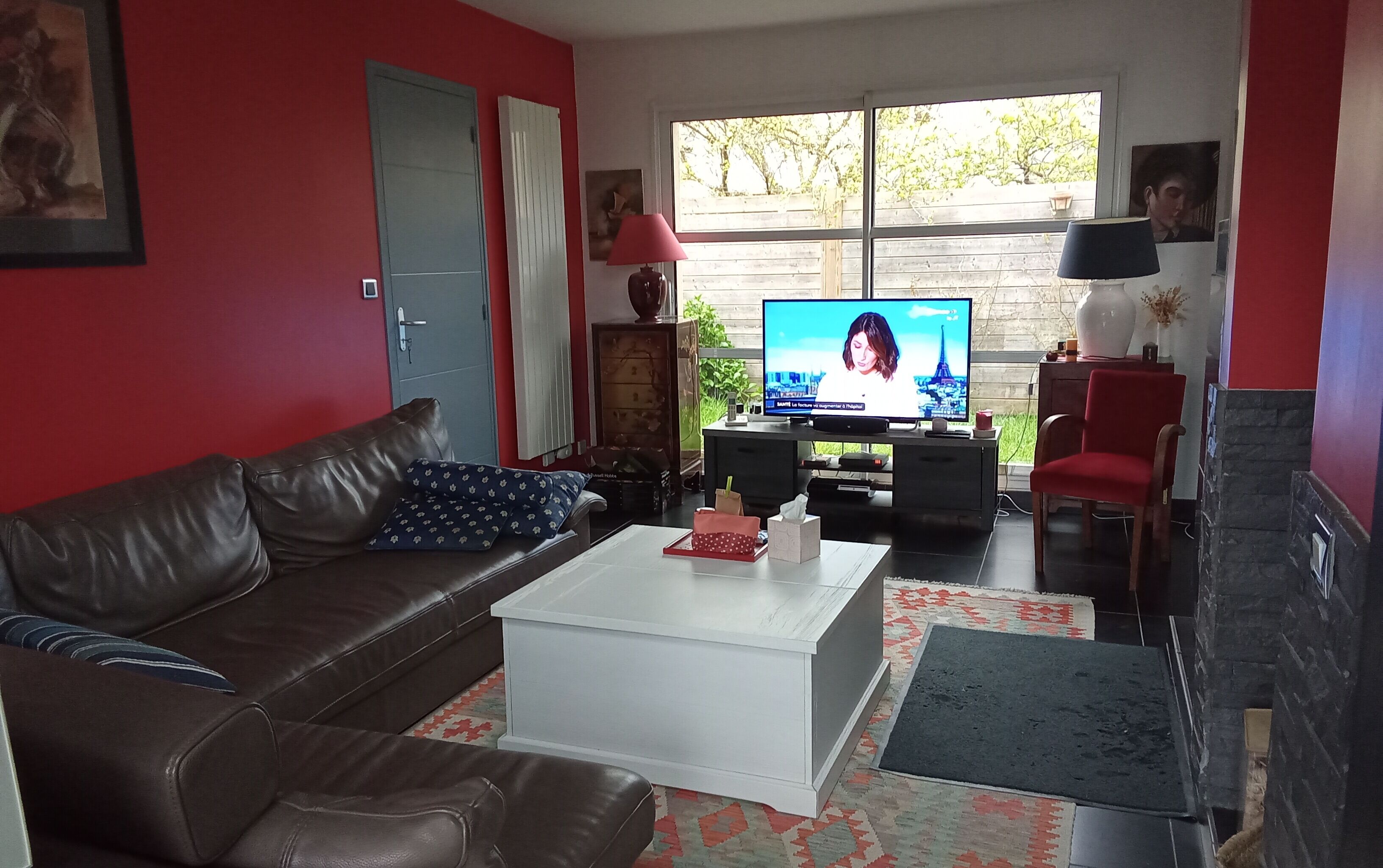Un salon avec un canapé en cuir marron, une table basse blanche, un téléviseur et une cheminée.