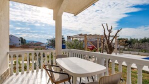 Ein überdachter Außenbereich mit Tisch und Stühlen, einer Pergola und Blick auf die umliegende Landschaft.