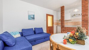 Ein modernes Wohnzimmer mit einem blauen Sofa, einem Holzesstisch und einer Küchenzeile mit einer Ziegelsteinsäule.