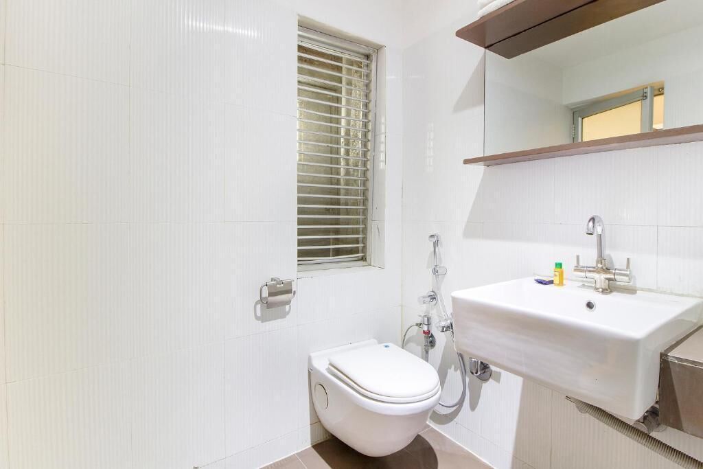 A bathroom with a toilet, sink, and window with blinds.