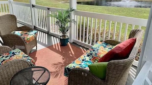 A covered outdoor seating area with wicker furniture and a potted plant. - Cozy Condo Near Baseball Fields and Zoo- Pool Tennis Courts Pickleball (Gulf Shores)