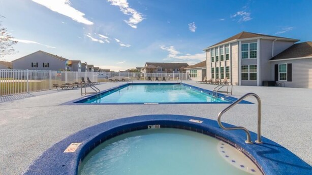 A swimming pool area with a hot tub, lounge chairs, and a fenced deck. - Cozy Condo Near Baseball Fields and Zoo- Pool Tennis Courts Pickleball (Gulf Shores)