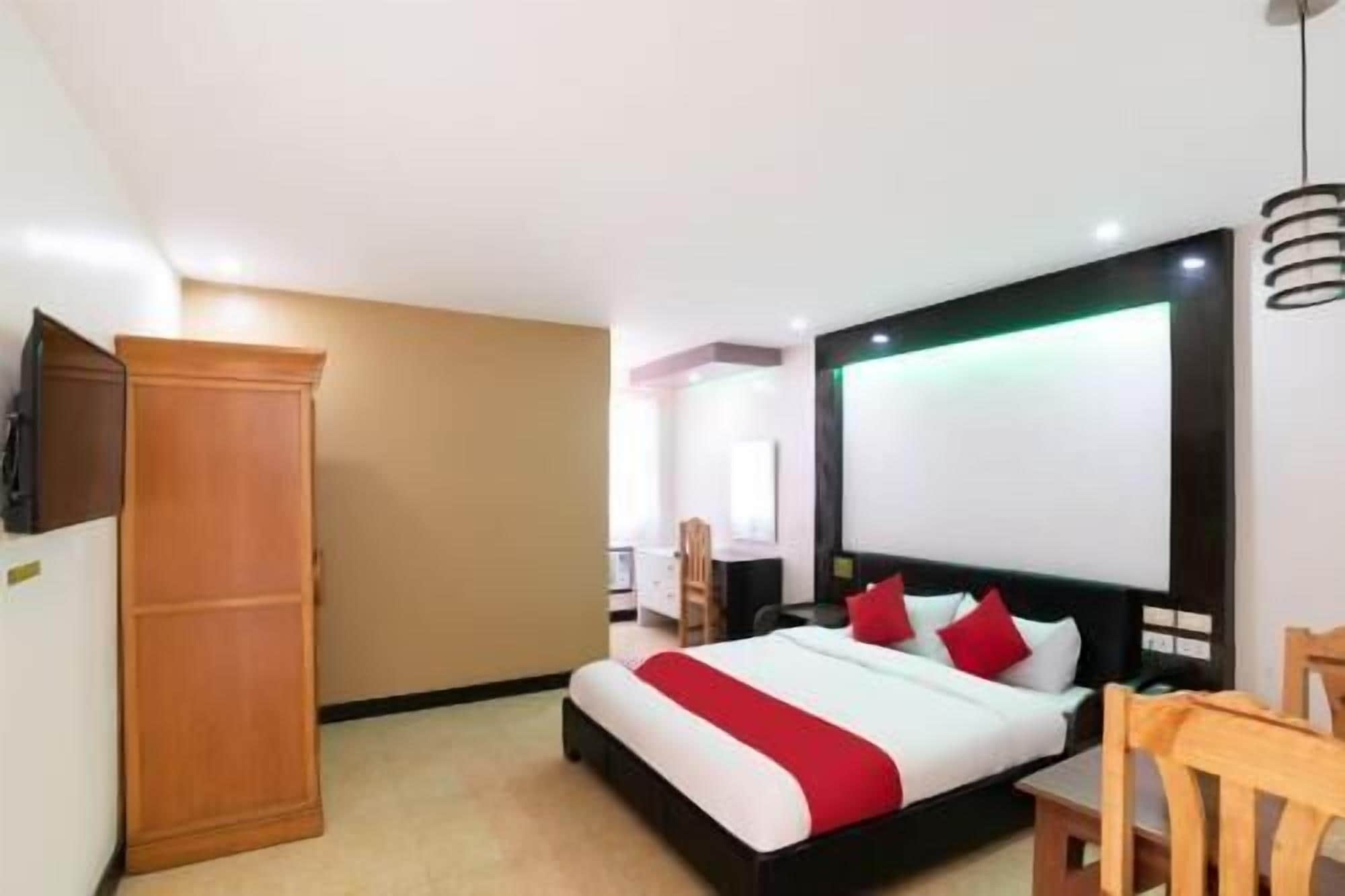 A hotel room with a bed, a wardrobe, a desk, and a TV.