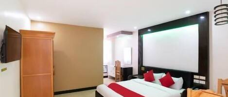 A hotel room with a bed, a wardrobe, a desk, and a TV.