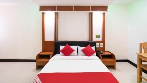Una habitación de hotel con cama, mesitas de noche y una silla.