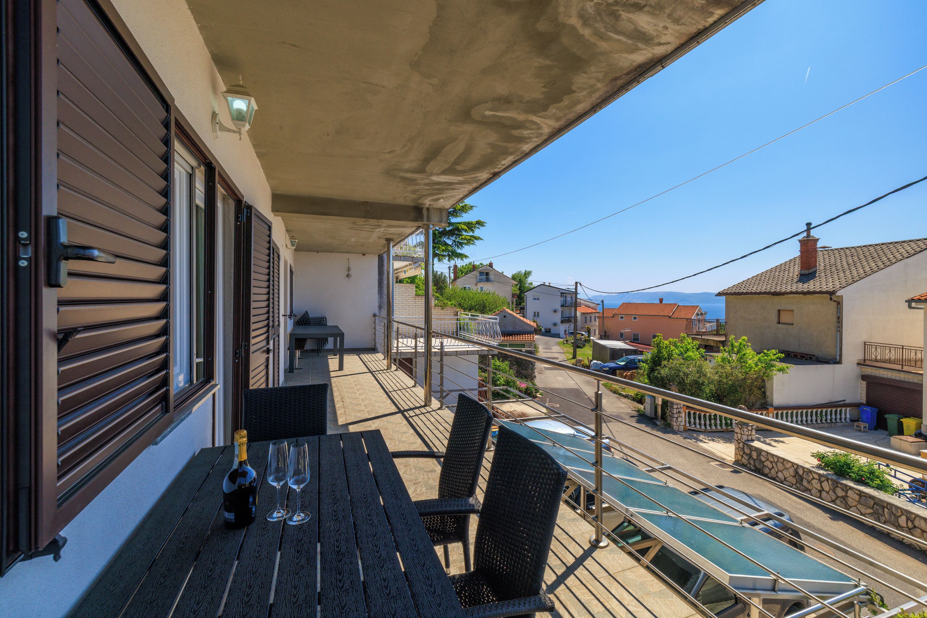 A balcony with a table, chairs, and a bottle of champagne.