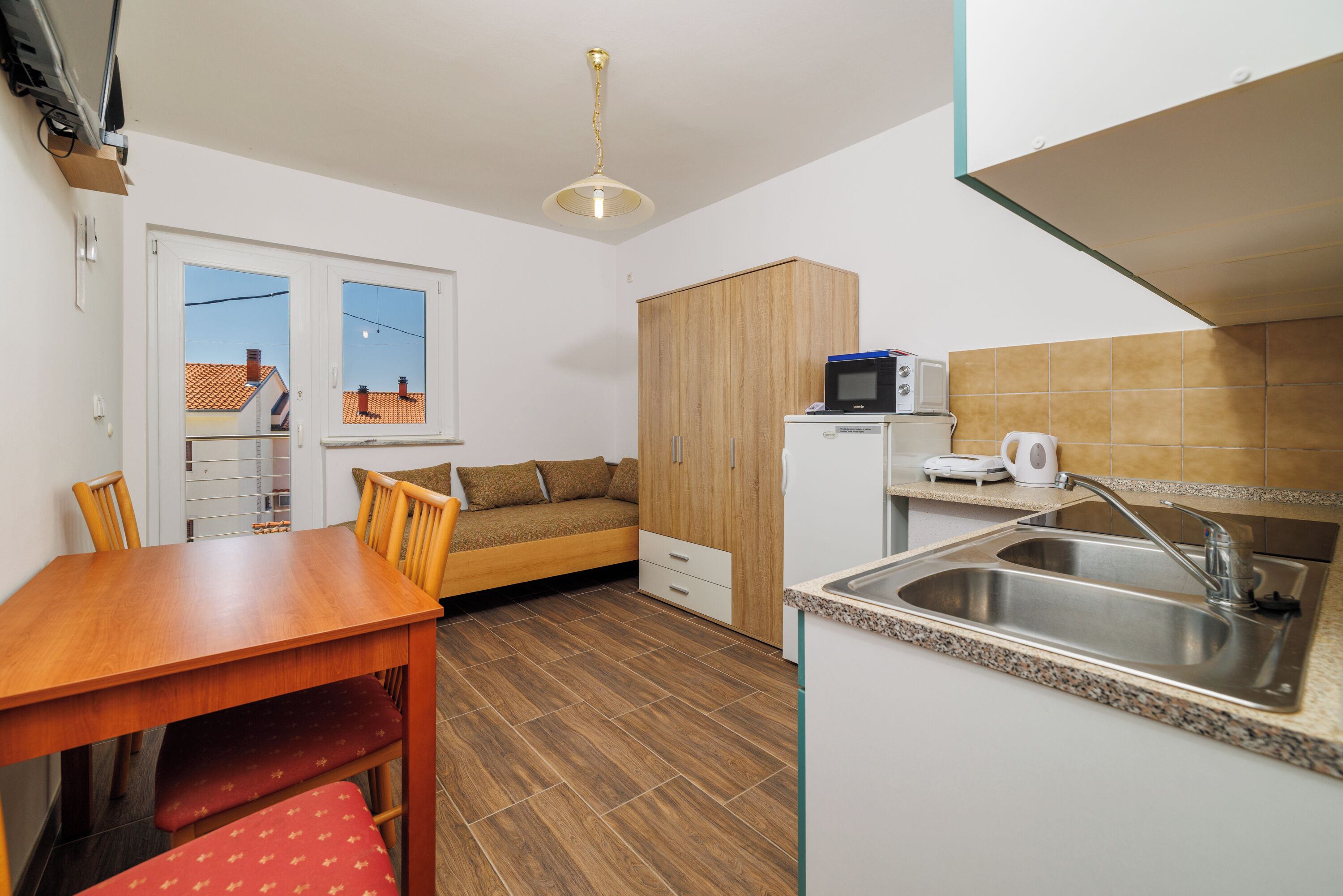Una cocina compacta con una mesa de comedor de madera, un microondas integrado y un lavamanos.