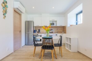 Eine moderne Küche mit weißen Schränken, einer eingebauten Mikrowelle und einem Edelstahl-Kühlschrank.