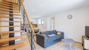 Ein modernes Wohnzimmer mit Treppe, grauem Sofa und einem kleinen runden Tisch.