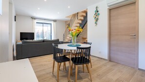 Ein moderner Wohnraum mit Essbereich, Treppe und Fernseher.