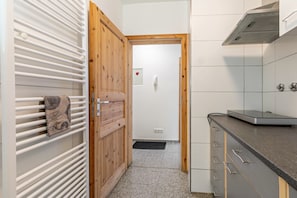 Cozinha com porta de madeira, toalha pendurada em um radiador, fogão e painel de azulejos.