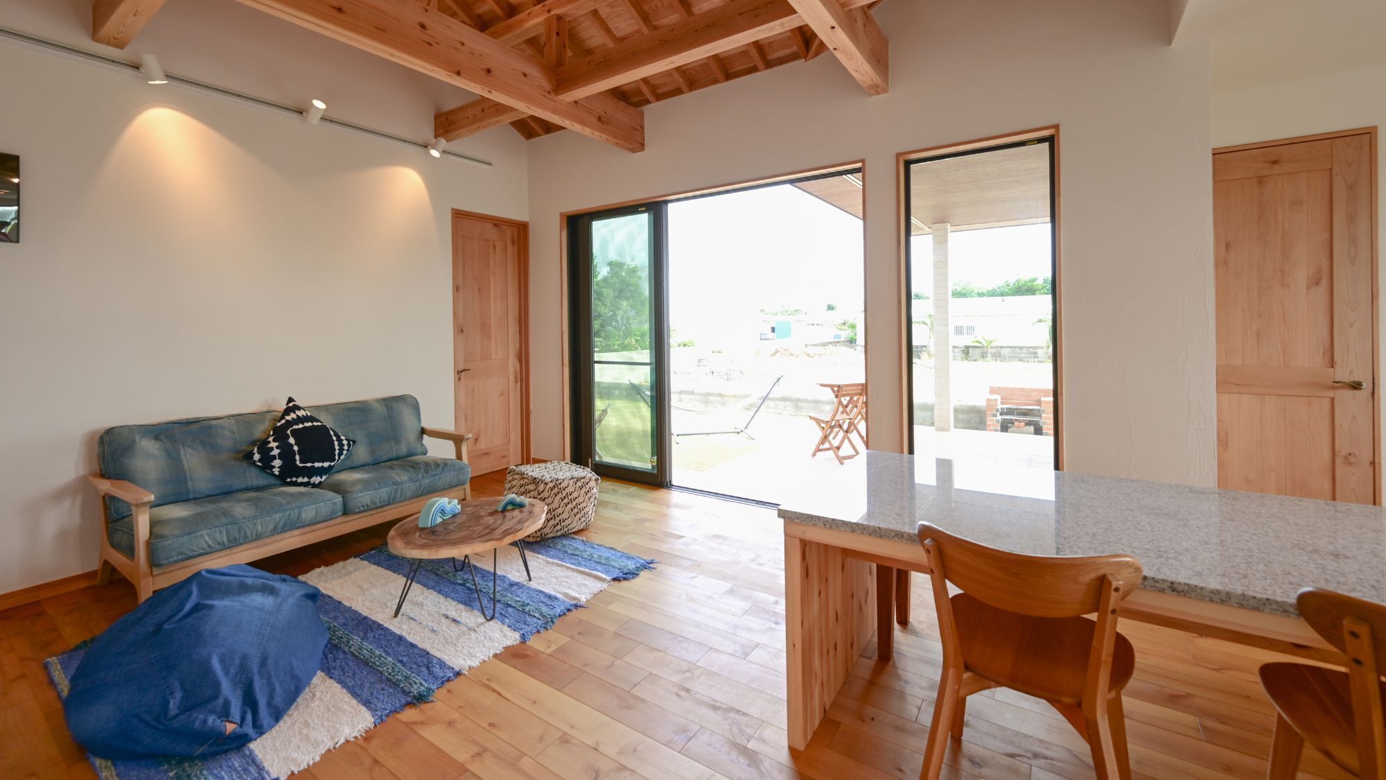 A modern living space with a wooden ceiling, a sofa, a coffee table, and a dining area.