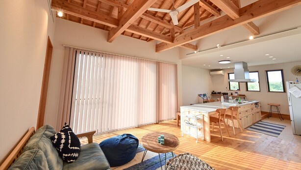 A spacious living area with a wooden ceiling, a sofa, a coffee table, and a kitchen in the background. - Ishigaki Island Villa 7716 (Ishigaki)