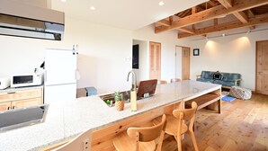 A modern kitchen with a granite countertop, wooden chairs, and a built-in stove. - Ishigaki Island Villa 7716 (Ishigaki)
