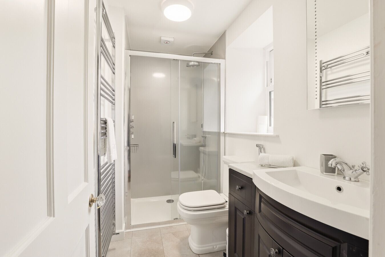 A modern bathroom with a glass-enclosed shower, a white toilet, a vanity with a sink, and a mirror above the sink.