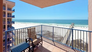 Un balcone con vista sulla spiaggia, una sedia e un tavolo.