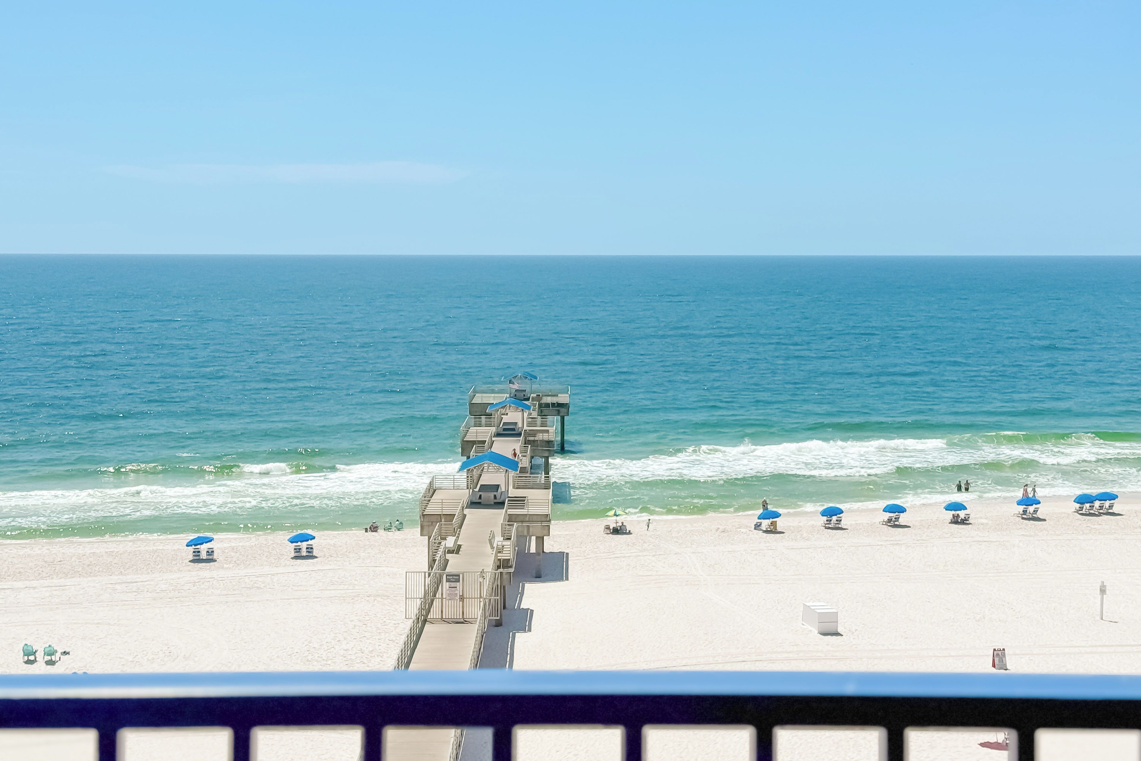A beach with a lifeguard tower, umbrellas, and a clear view of the ocean.