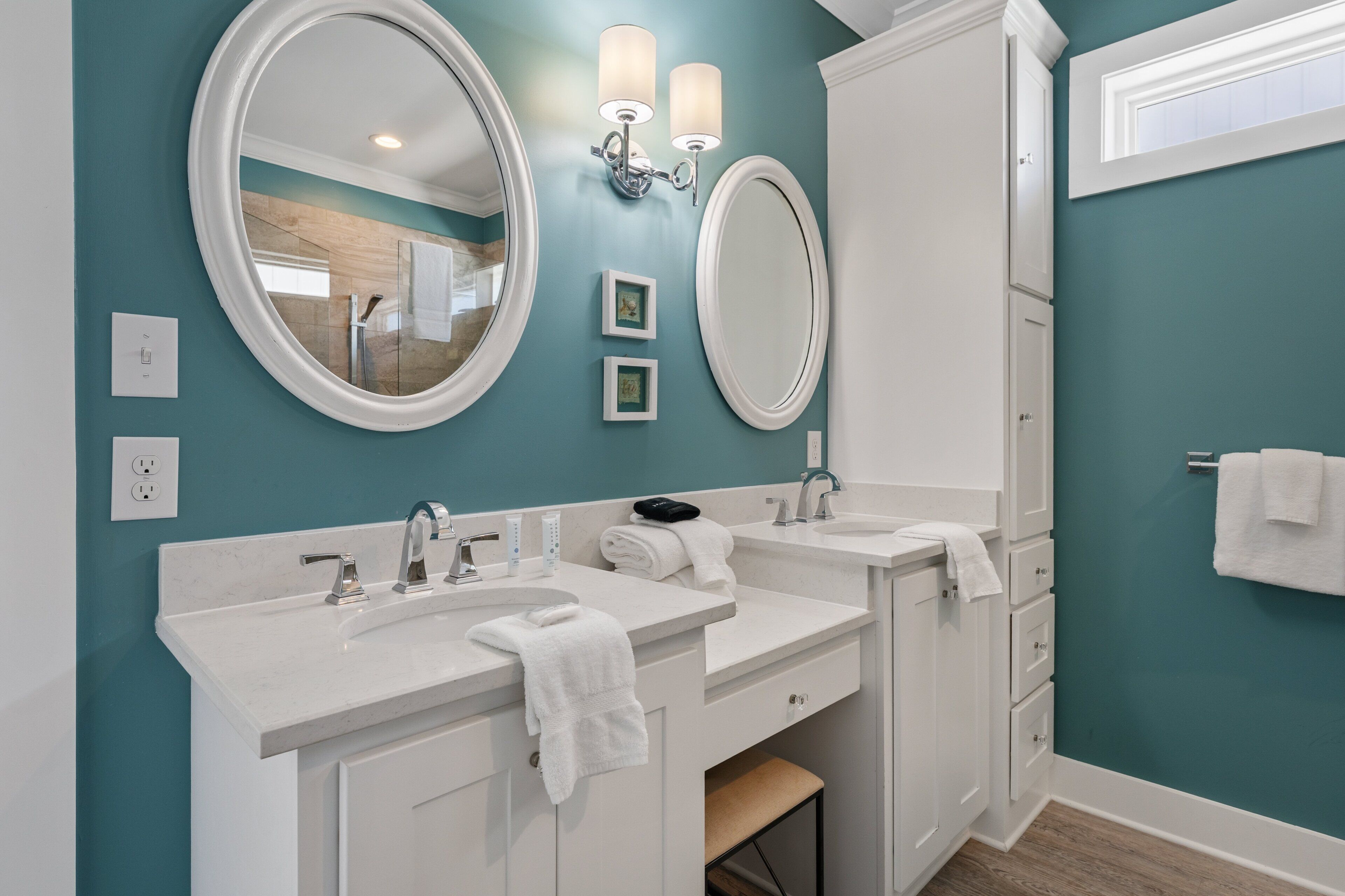 A bathroom with two sinks, a large mirror, wall sconces, and a towel rack.