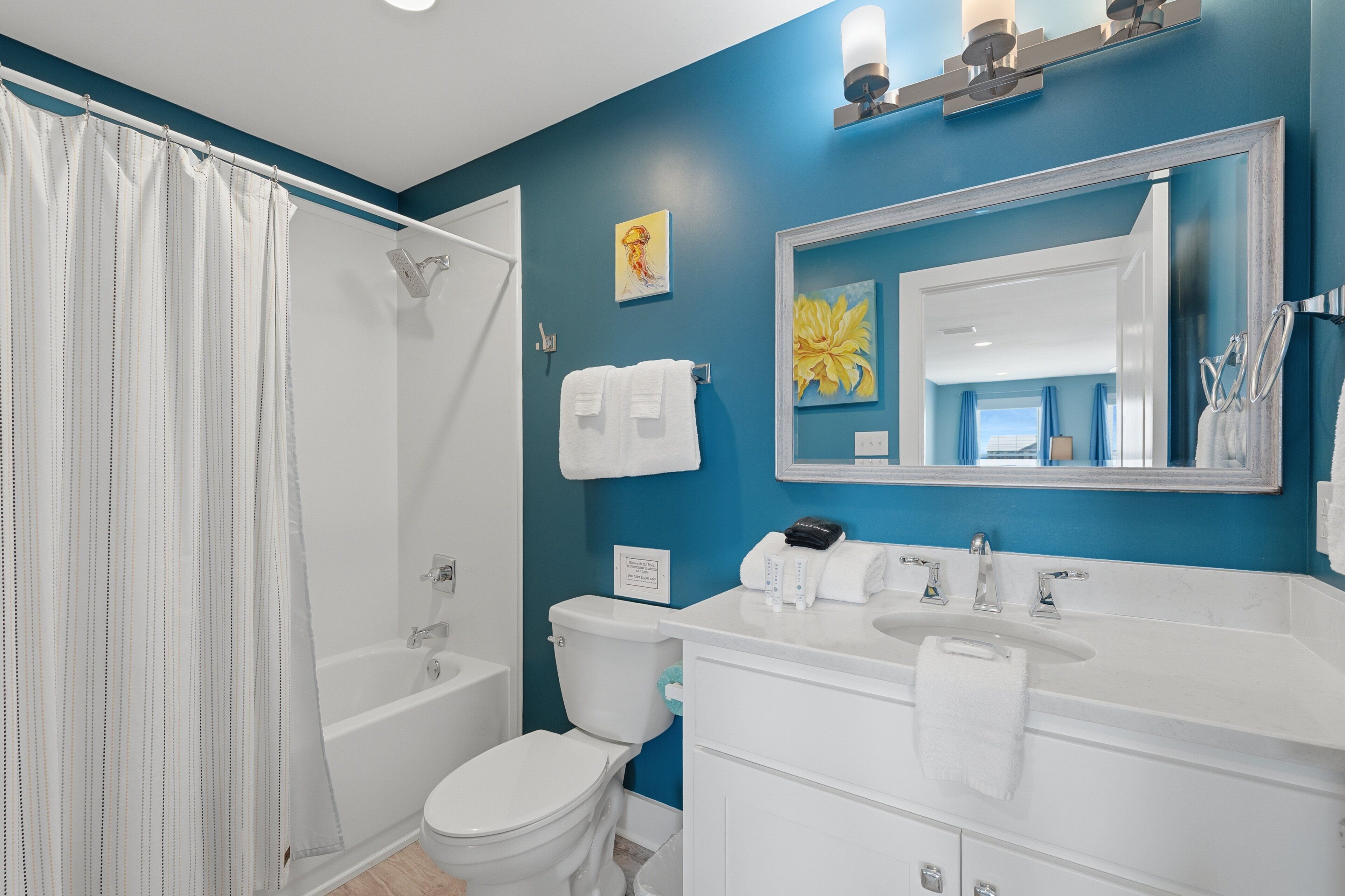 A bathroom with a bathtub, toilet, sink, and a large mirror.