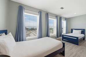 Hotellihuone, jossa on kaksi sänkyä, suuret ikkunat, joissa on verhot, näkymä kaupunkiin ja moderni sisustus.