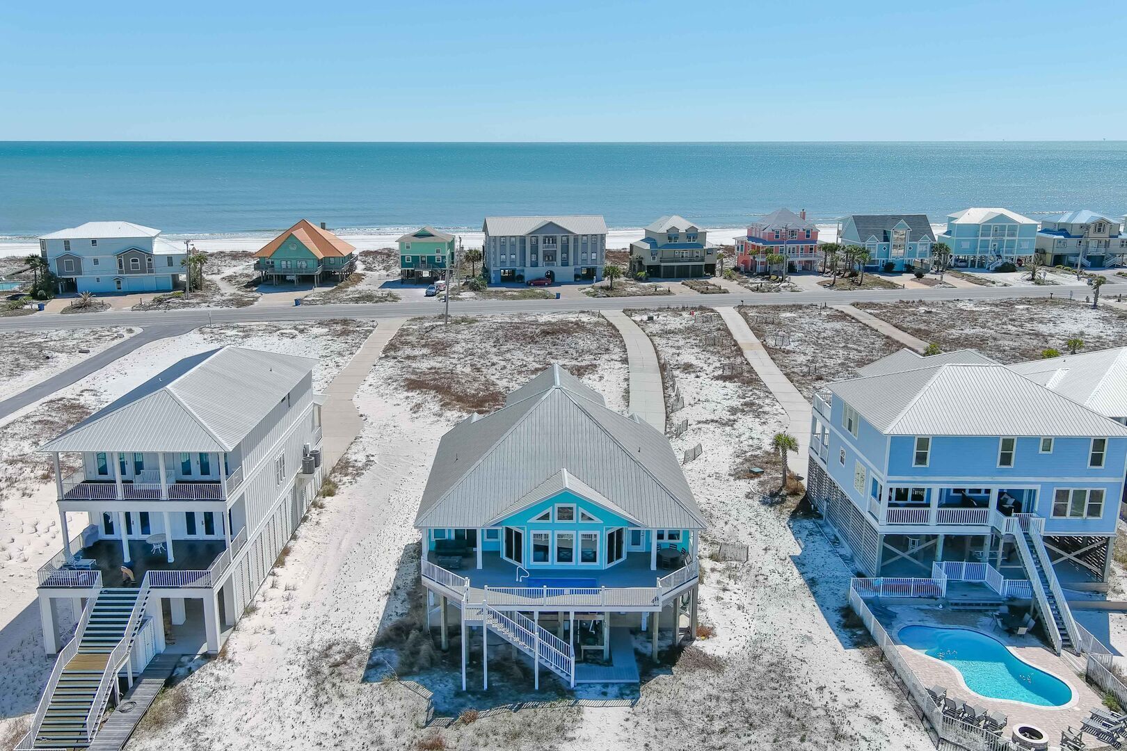 A beachfront property with multiple houses, a swimming pool, and a beach view.