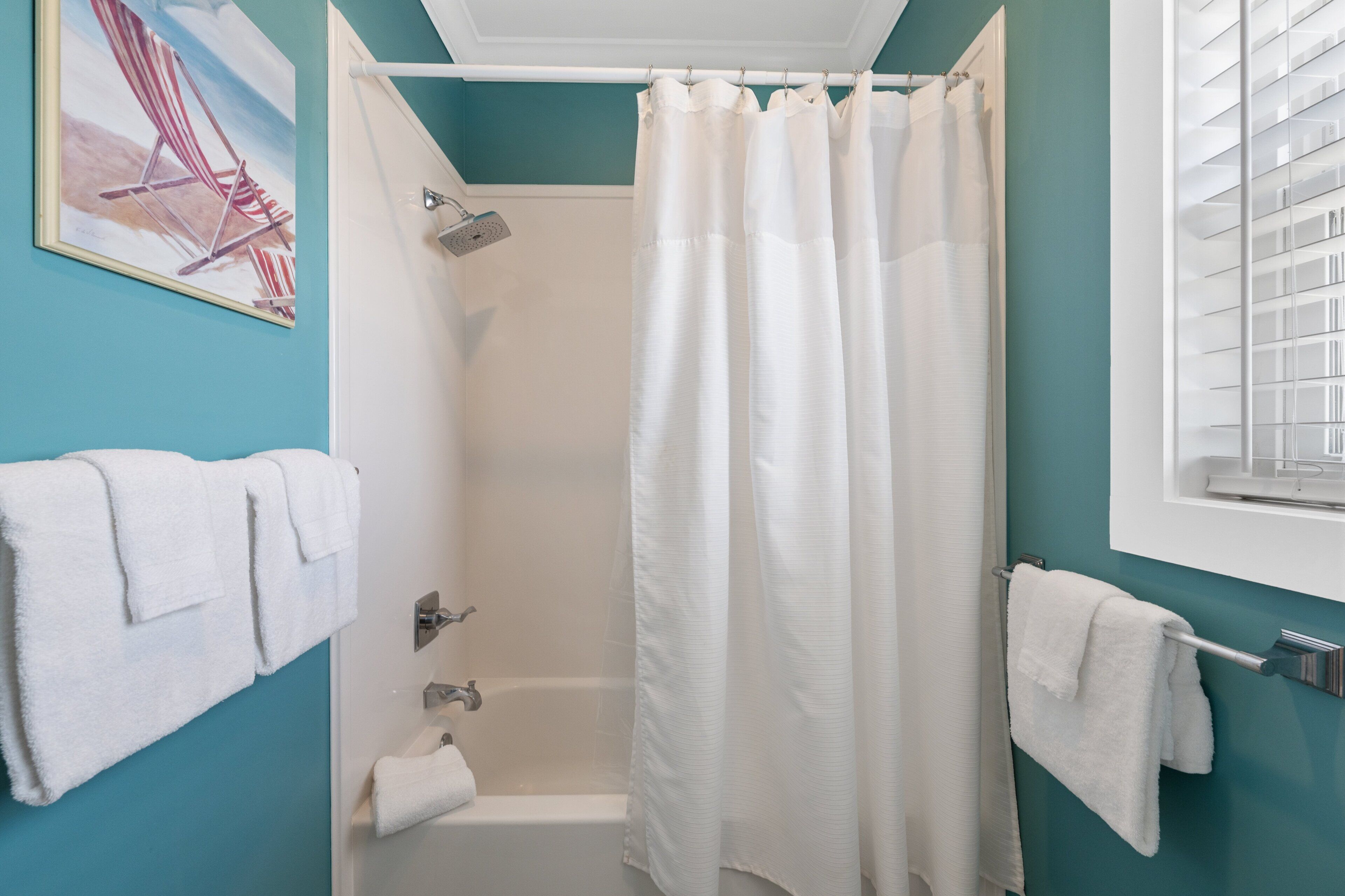A bathroom with a shower, a bathtub, and a window with blinds.