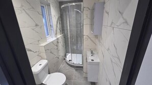 Une salle de bain moderne équipée de toilettes, d’une douche et d’un meuble-lavabo.