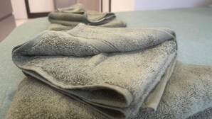 Une serviette verte, soigneusement pliée, est posée sur un lit dans une chambre d’hôtel.