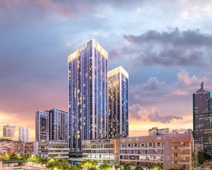 A high-rise building with multiple floors, surrounded by other buildings and trees.