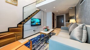Una sala de estar moderna con una escalera, un televisor de pantalla plana, un sofá y una mesa de centro.