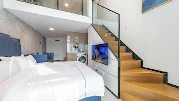 Un dormitorio moderno con una cama grande, un televisor y una escalera que lleva a un nivel superior.