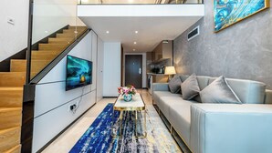 Una sala de estar moderna con una escalera, un televisor de pantalla plana, un sofá y una mesa de centro.