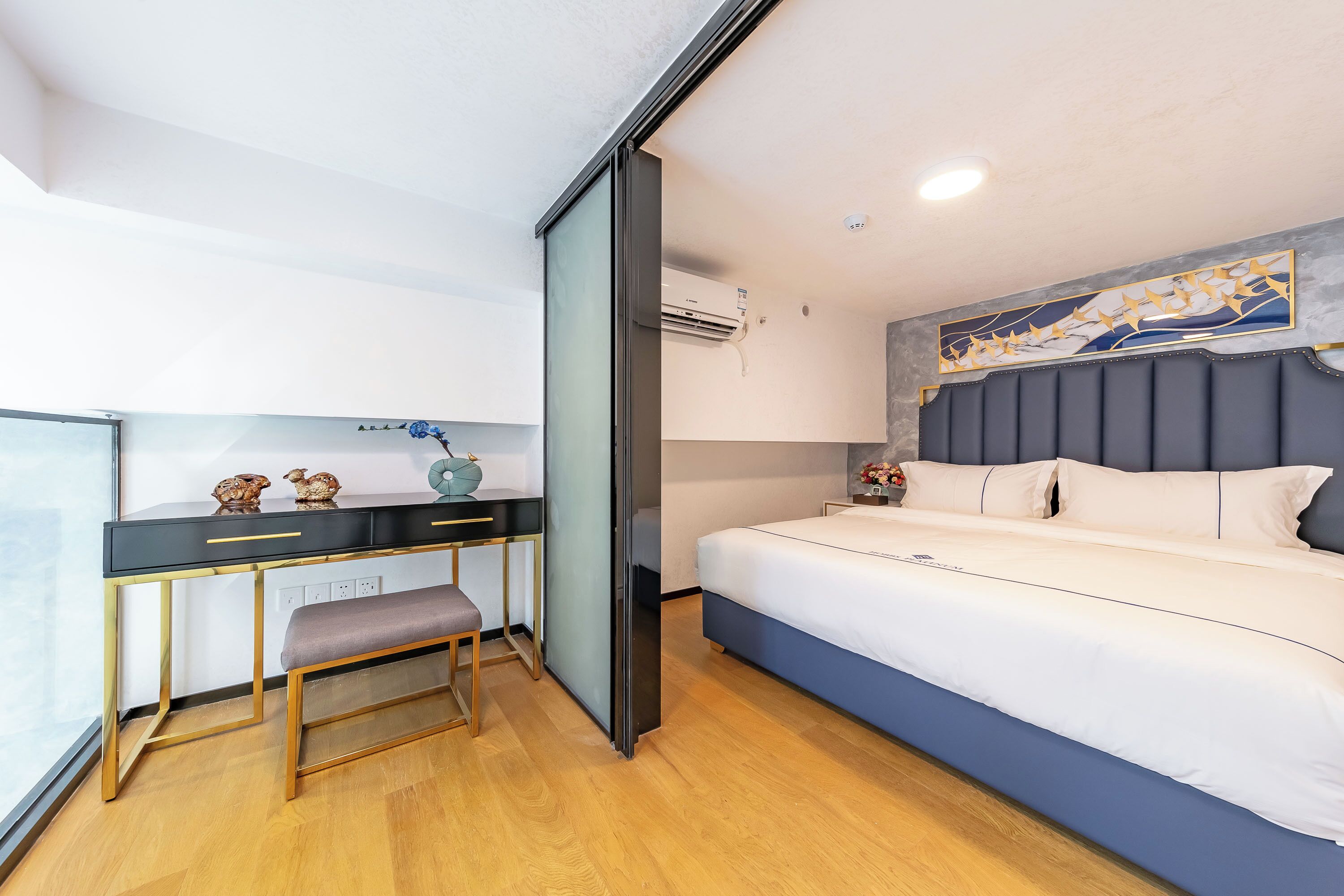 Moderni hotellihuone, jossa on sänky, työpöytä tuolilla ja ikkuna.