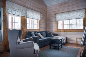 A log cabin interior with a sofa, armchair, and a small table.