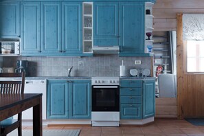 A kitchen with teal cabinets, a white stove, and a microwave.