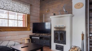 Uma sala de estar aconchegante com televisão, lareira e paredes de madeira.