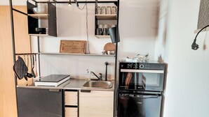 Een kleine keuken met een spoelbak, een fornuis en een koelkast.