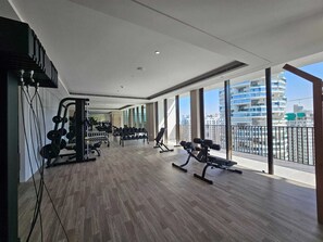 Ein modernes Fitnessstudio mit Trainingsgeräten, großen Fenstern und Blick auf die Stadt.