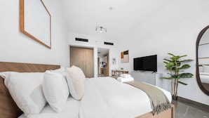 Une chambre d’hôtel moderne avec un grand lit, une télévision, un miroir et une plante en pot.