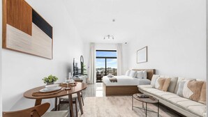 Une chambre d’hôtel moderne dotée d’un coin repas, d’un canapé, d’une table basse et offrant une vue sur la ville.