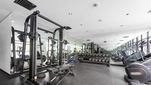 Une salle de sport équipée de machines d’exercice, de tapis de course et de supports pour les poids.
