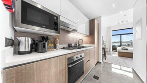 Une cuisine moderne équipée d’un four à micro-ondes, d’une cuisinière et d’un four, dotée d’une grande fenêtre offrant une vue sur la ville et arborant un design minimaliste.