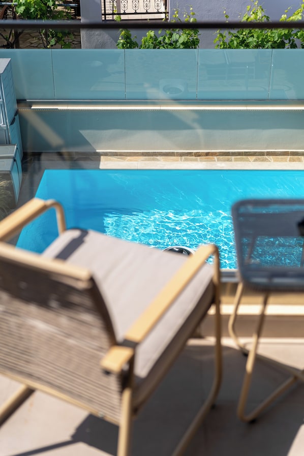 Zona junto a la piscina con dos sillones de descanso y vista despejada al agua.