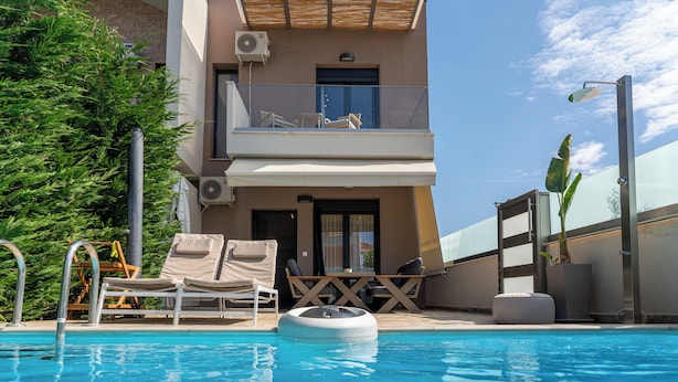 Un área de piscina con sillas de descanso, una plataforma flotante y un edificio con balcón.