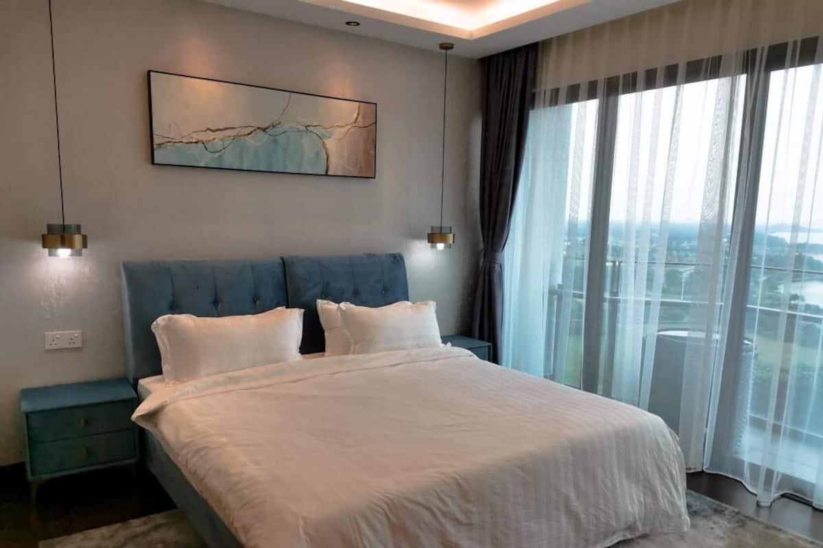 Quarto moderno com uma cama grande, vista para a cidade e um quadro na parede.