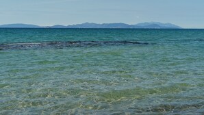 Une vue dégagée sur une zone côtière, avec des eaux calmes et des montagnes à l’horizon.