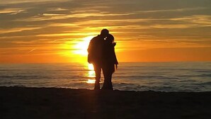 La silhouette d’une personne se tenant sur une plage au coucher du soleil.