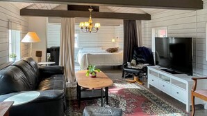 Ein Wohnzimmer mit Sofa, Couchtisch, Fernseher, einer Chandelieber und einem Bett.