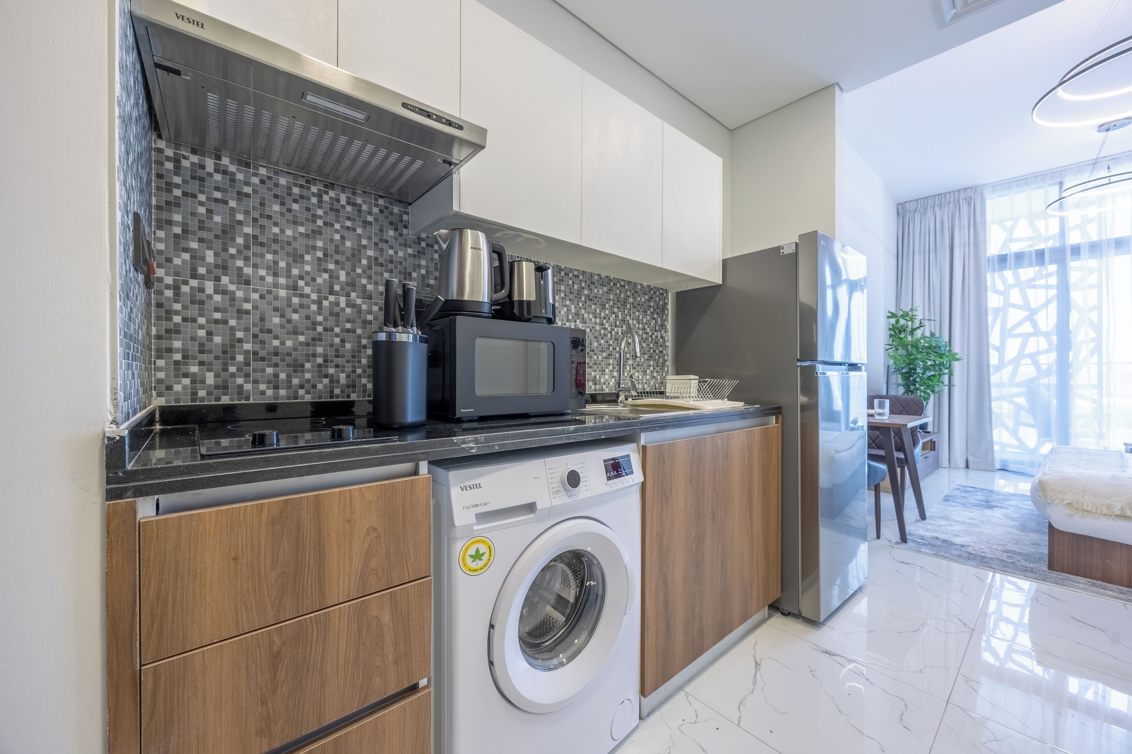 A modern kitchen with a built-in washing machine, a microwave, and a stainless steel range hood.