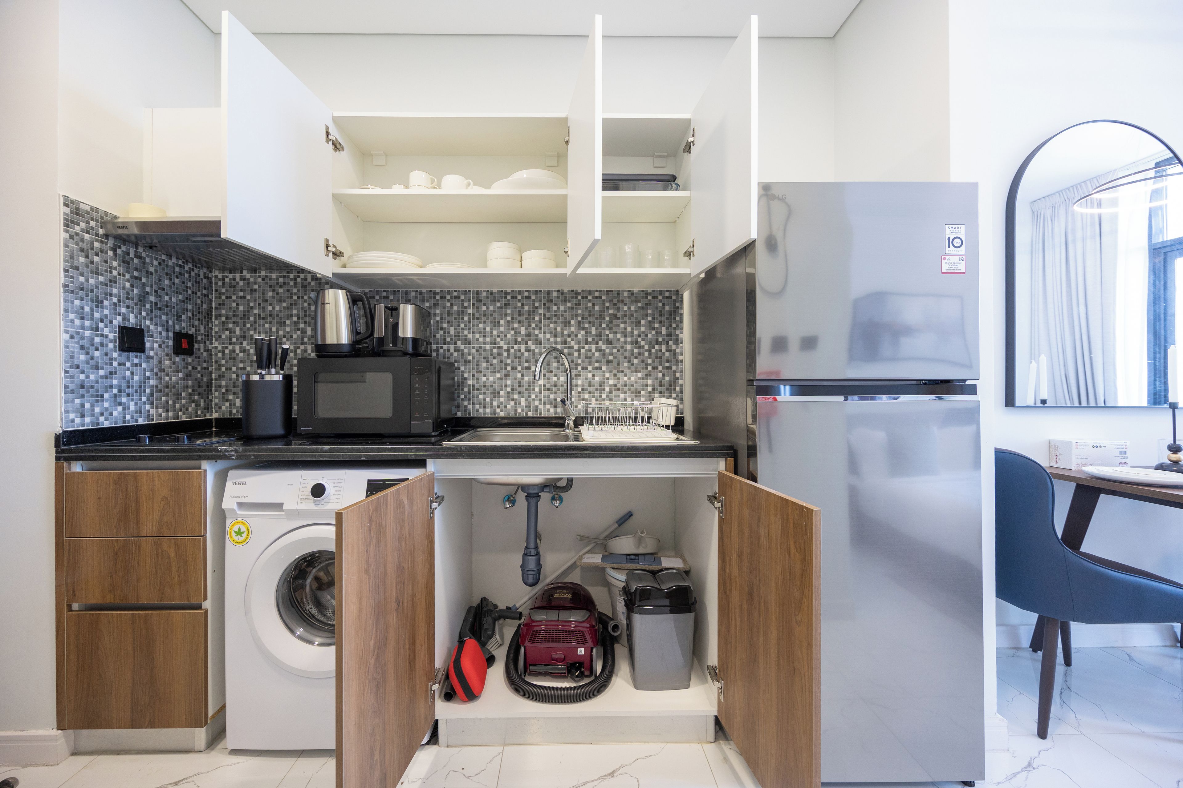 A compact kitchen with a washing machine, a microwave, and a refrigerator.